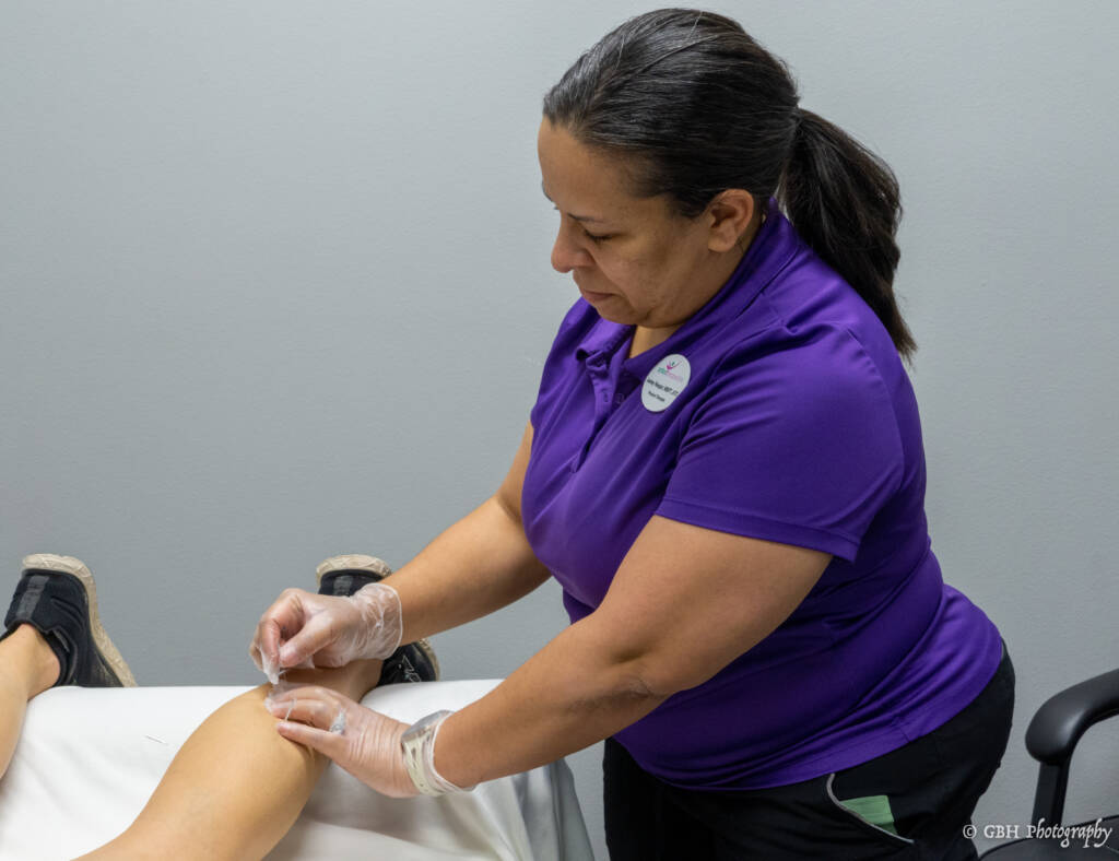 A woman in purple shirt working on her arm.