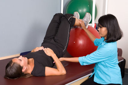 A woman is stretching on the table while another person assists.