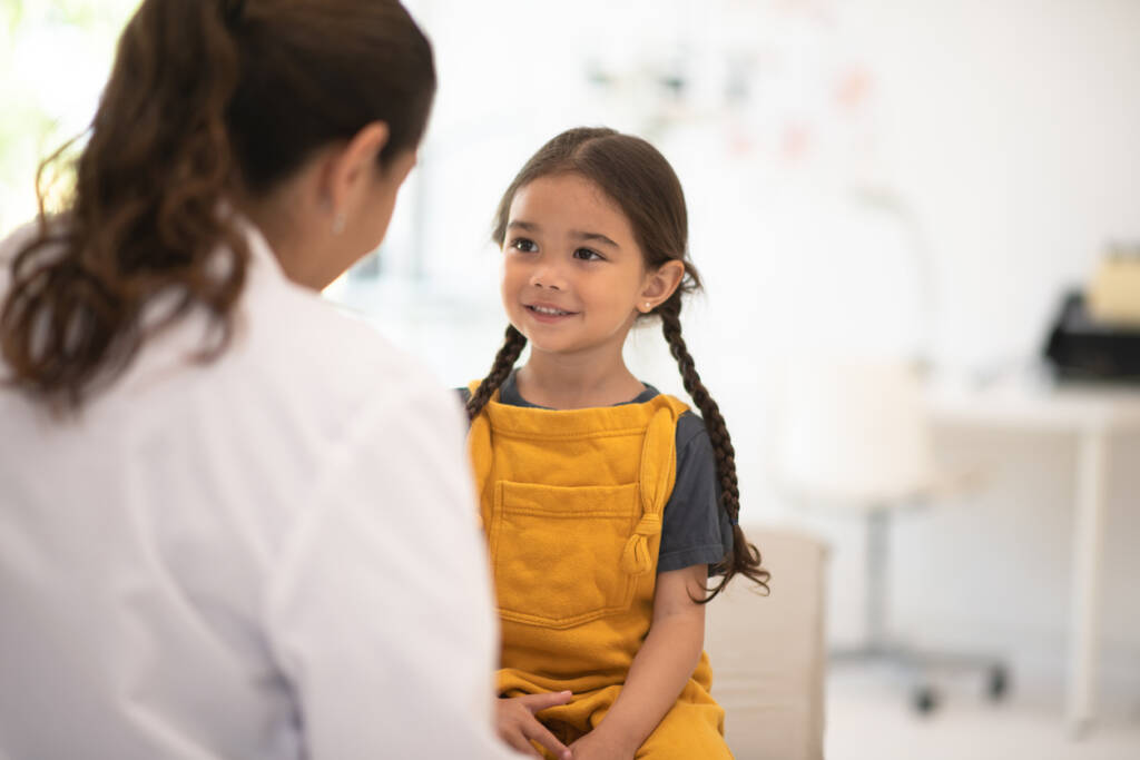 A young girl is smiling at the doctor.