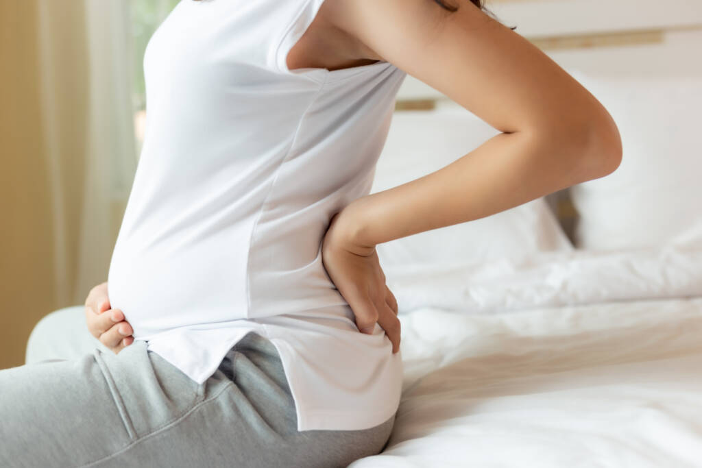 A woman sitting on top of a bed with her back turned.